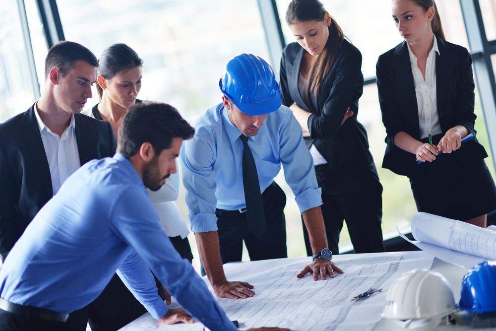 Equipo de seis profesionales observando un plano de un proyecto