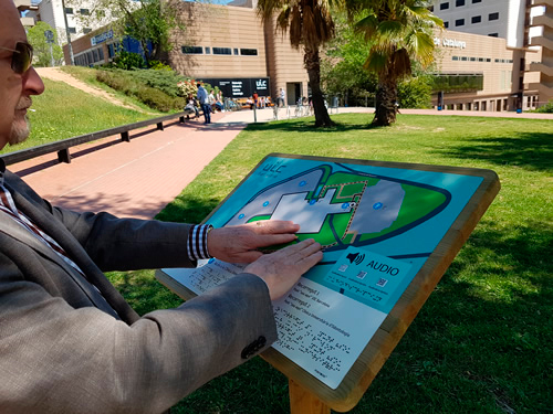 adulto mayor tocando un plano tactovisual de un establecimiento recreativo